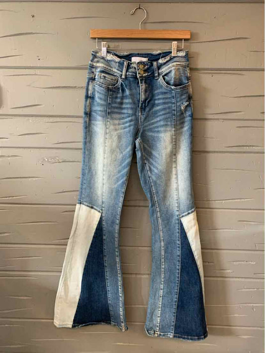 High-waisted flared jeans with blue denim patchwork and light beige fabric panels on lower legs.