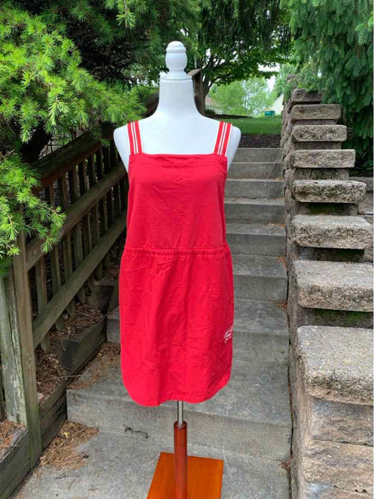 Red sleeveless square-neck dress with gathered waist and adjustable straps on white mannequin outdoors.
