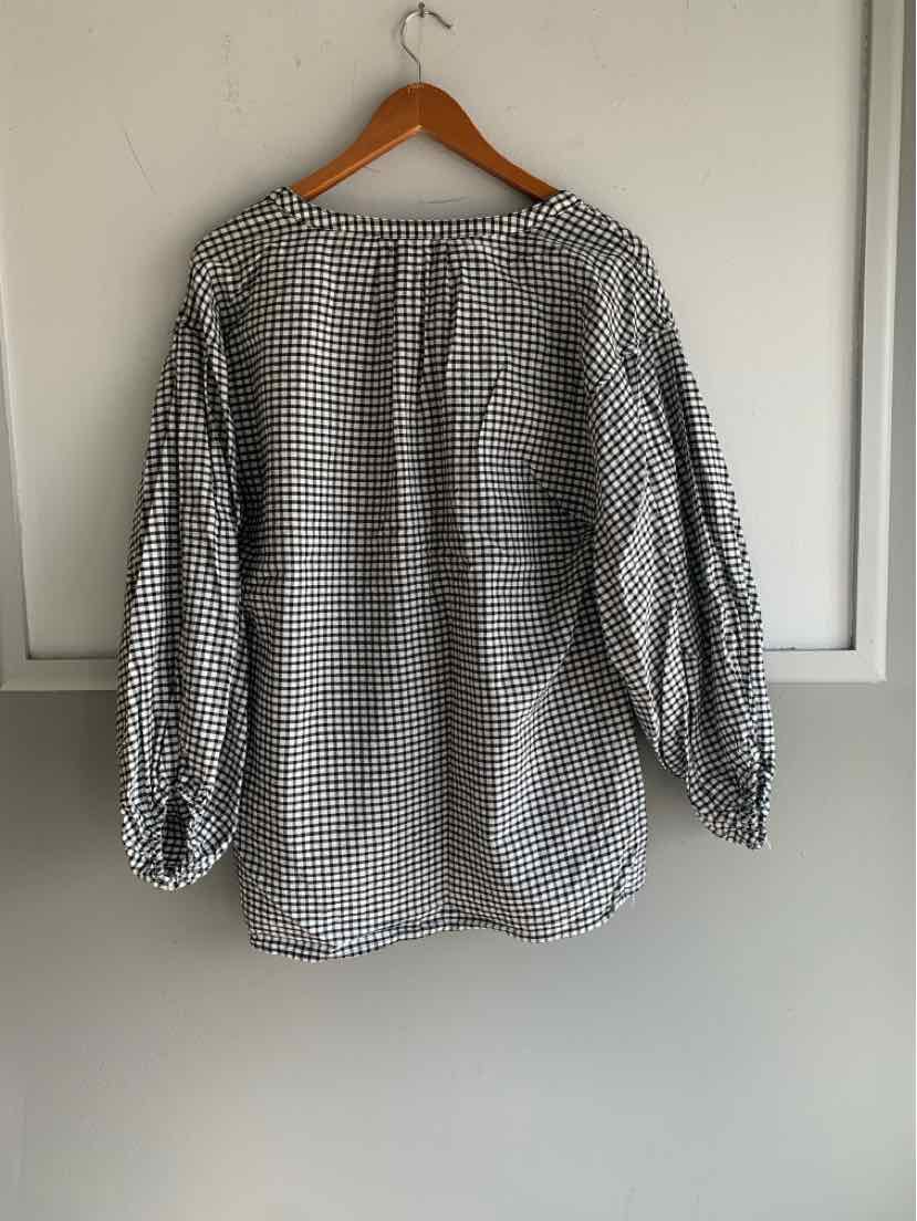 Black and white gingham long-sleeve blouse with gathered cuffs hanging on wooden hanger.