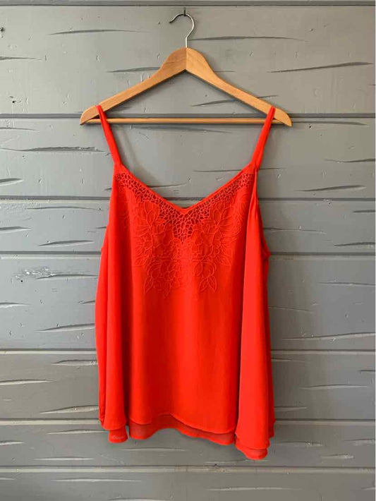 Red sleeveless camisole top with lace trim neckline on a wooden hanger.