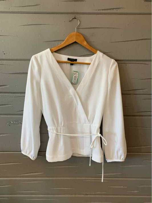 White long-sleeve wrap top with V-neck and side tie detail on wooden hanger.