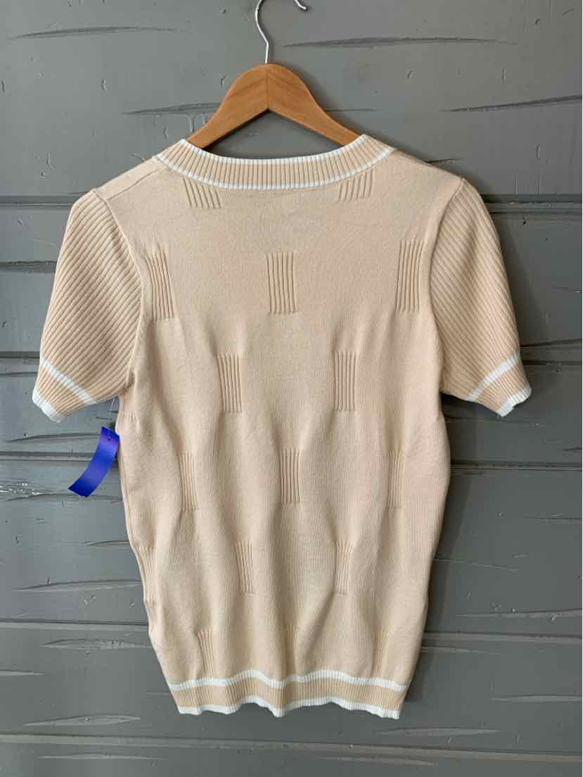 Beige knit sweater with short sleeves and white trim on collar and cuffs hanging on wooden hanger against gray background.