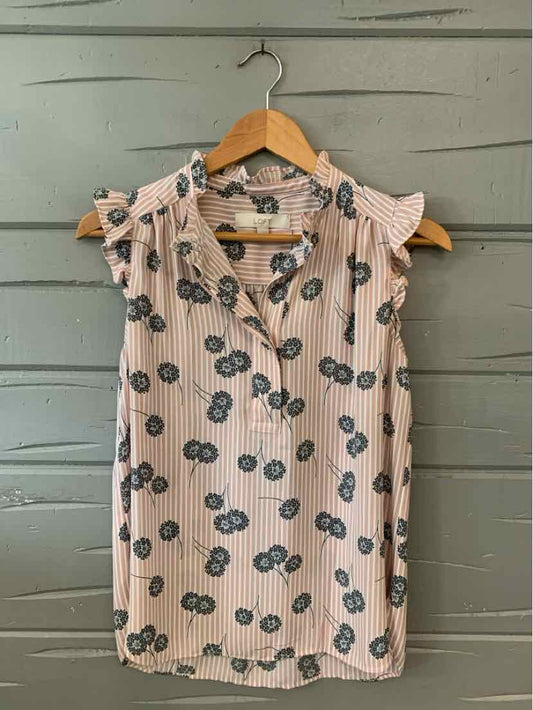 Light pink sleeveless blouse with large dark floral prints and ruffled shoulders.