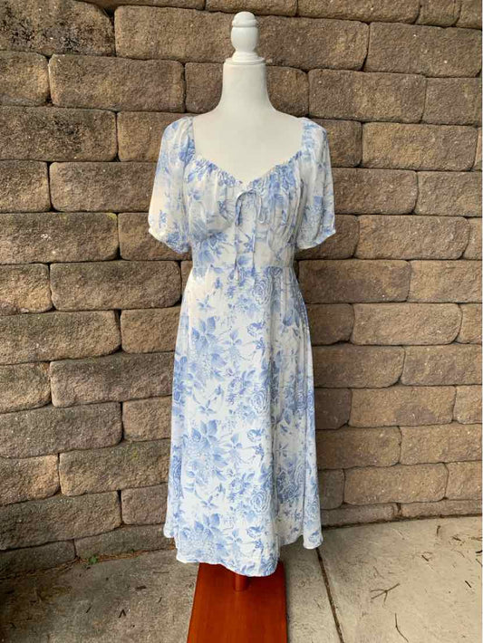 White midi dress with blue floral pattern, puff sleeves, and a fitted waist.