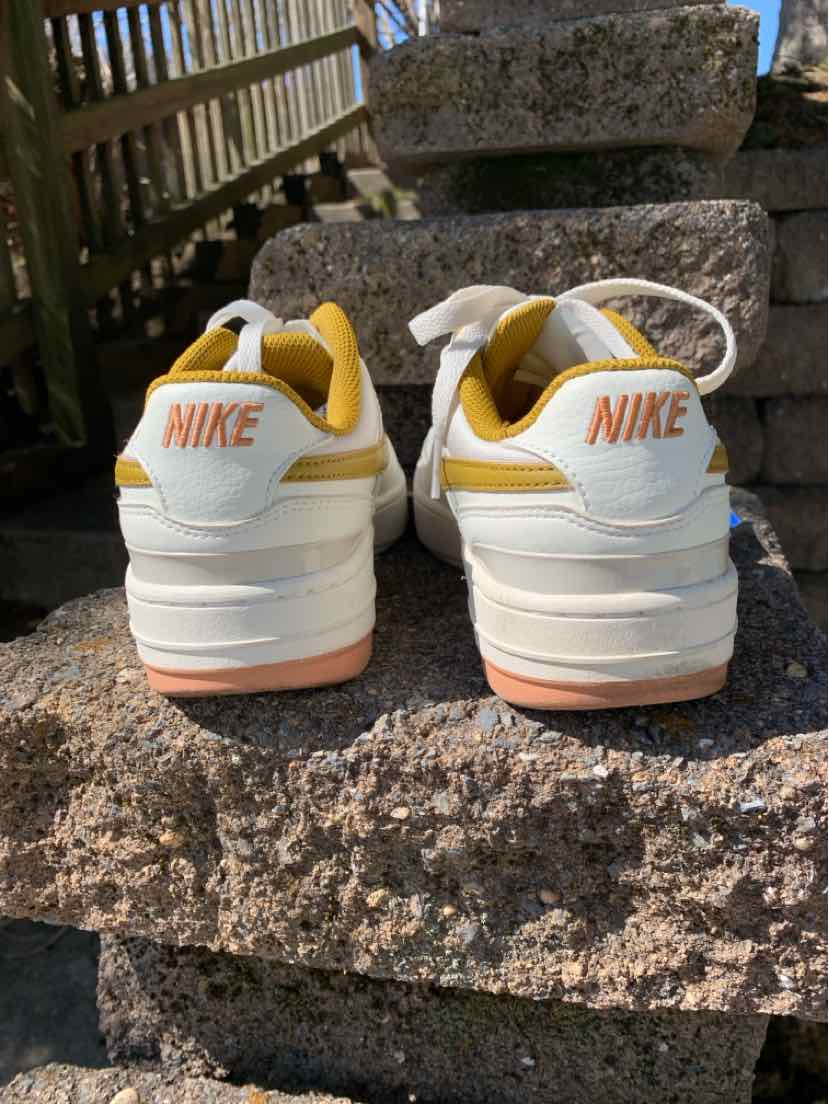 White and yellow Nike sneakers with orange Nike logo on heel, size 8, textured sole.