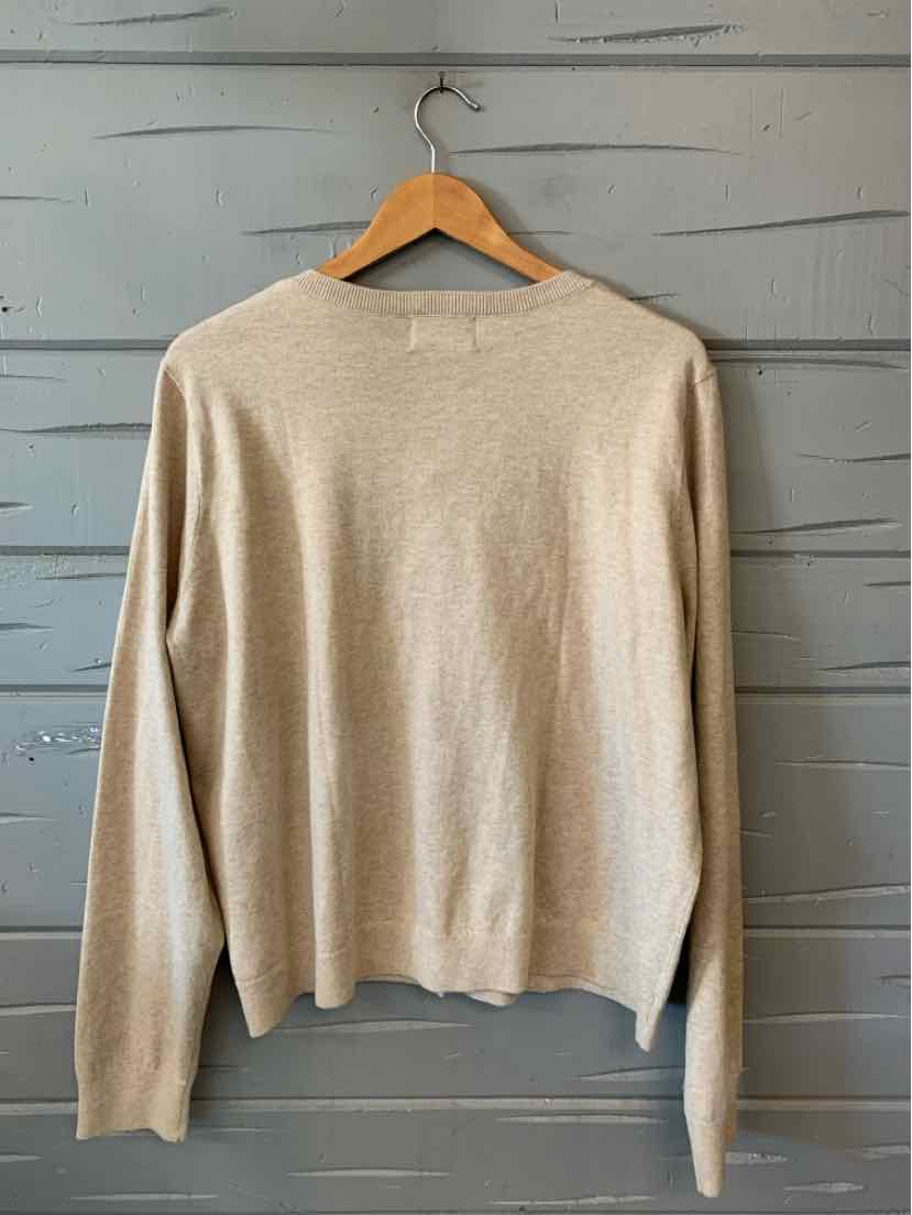 Tan long-sleeve knit sweater with crew neckline and relaxed fit hanging on wooden hanger.
