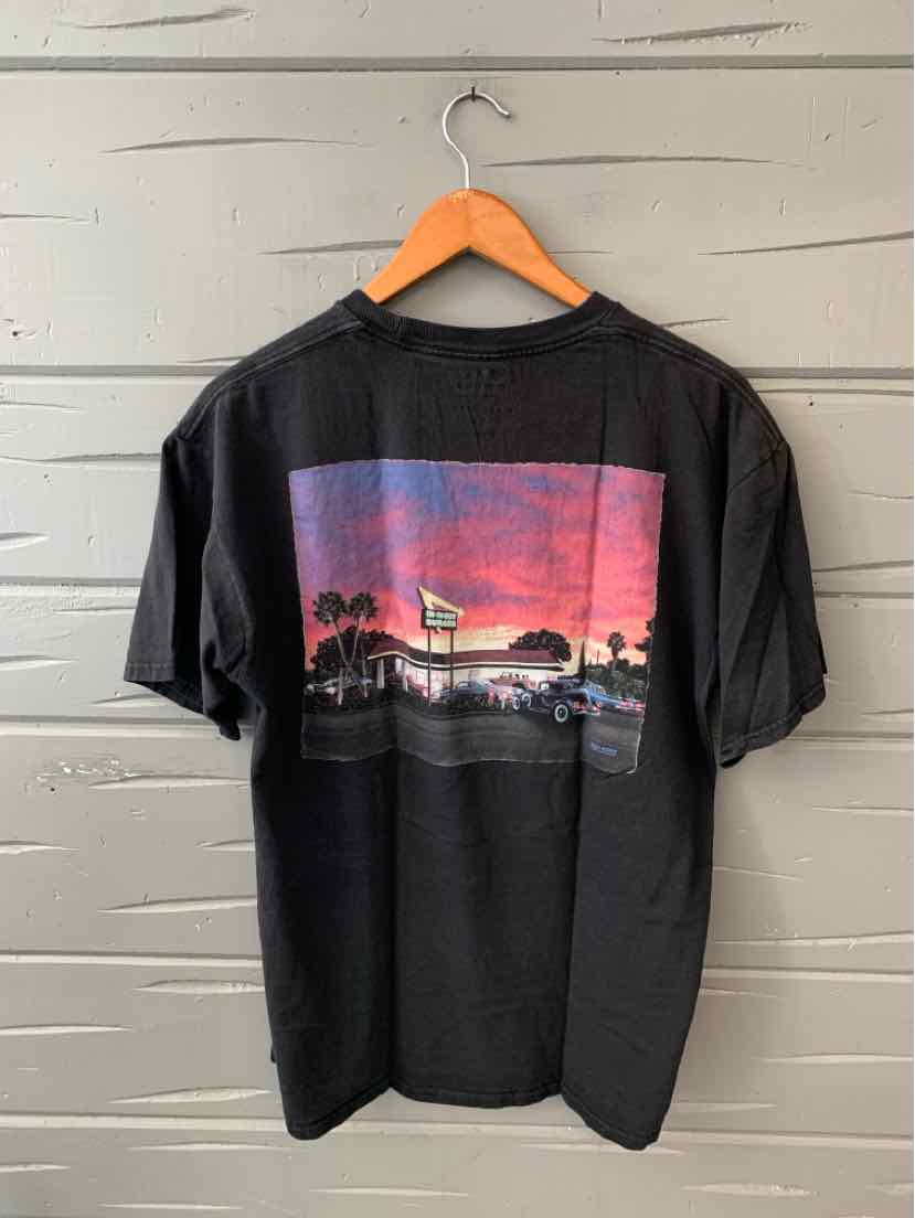Black short-sleeve T-shirt with a large colorful graphic of a sunset beach scene on the back.