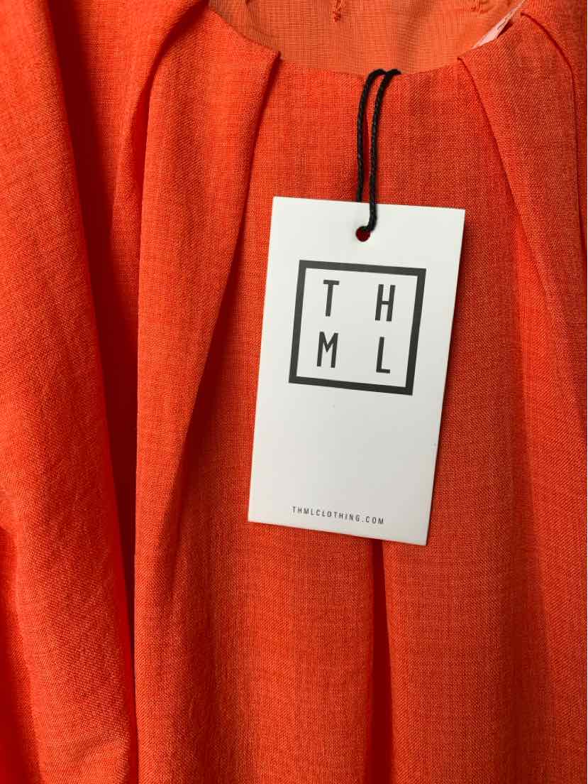Orange textured fabric dress with round neckline and THML brand tag attached by black string.