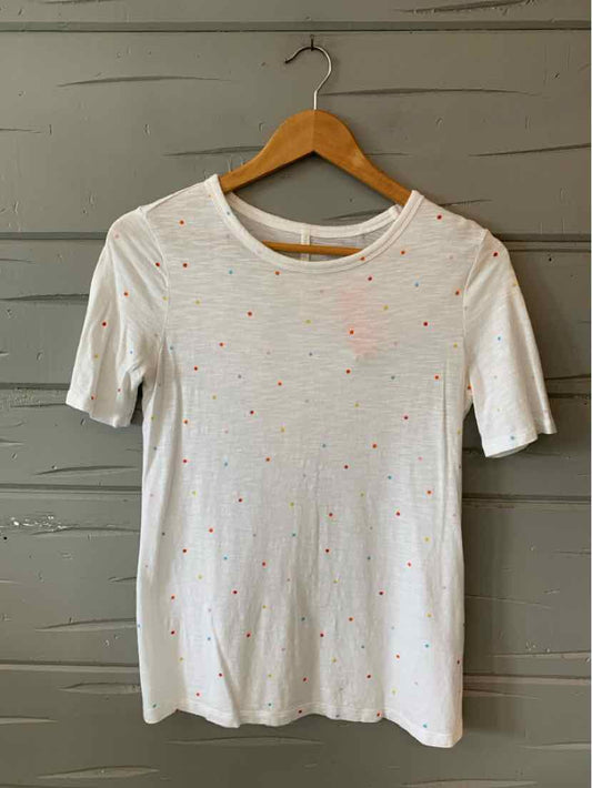 White short-sleeve fitted top with small multicolored polka dots and round neckline.