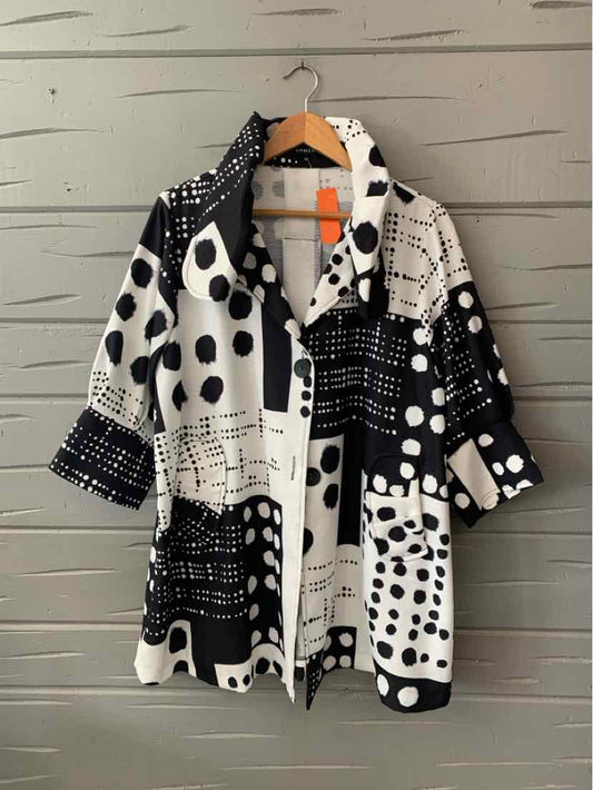 Black and white oversized jacket with mixed polka dot and grid patterns, rolled sleeves, and button closure.