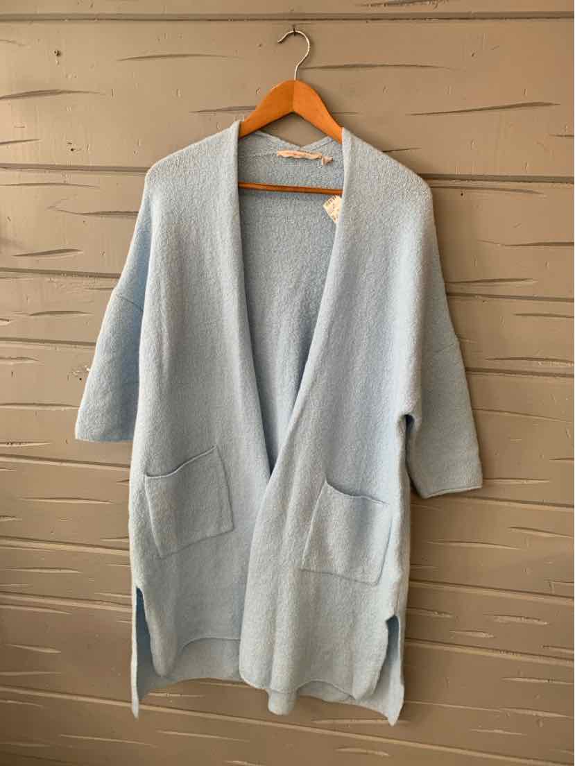 Light blue open-front knit cardigan with two front pockets and three-quarter sleeves on wooden hanger.