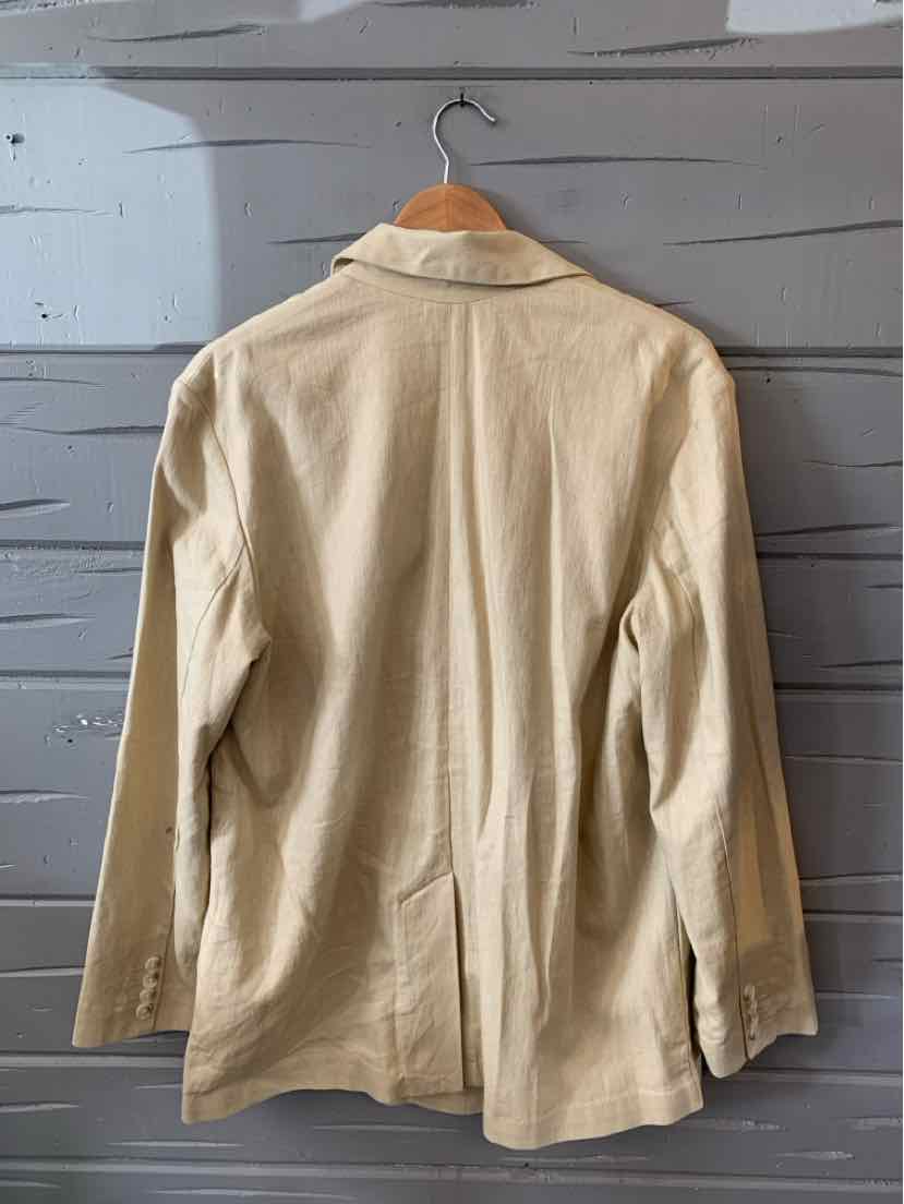 Tan long-sleeve blazer with notch collar, tailored fit, and back vent hanging on wooden hanger.