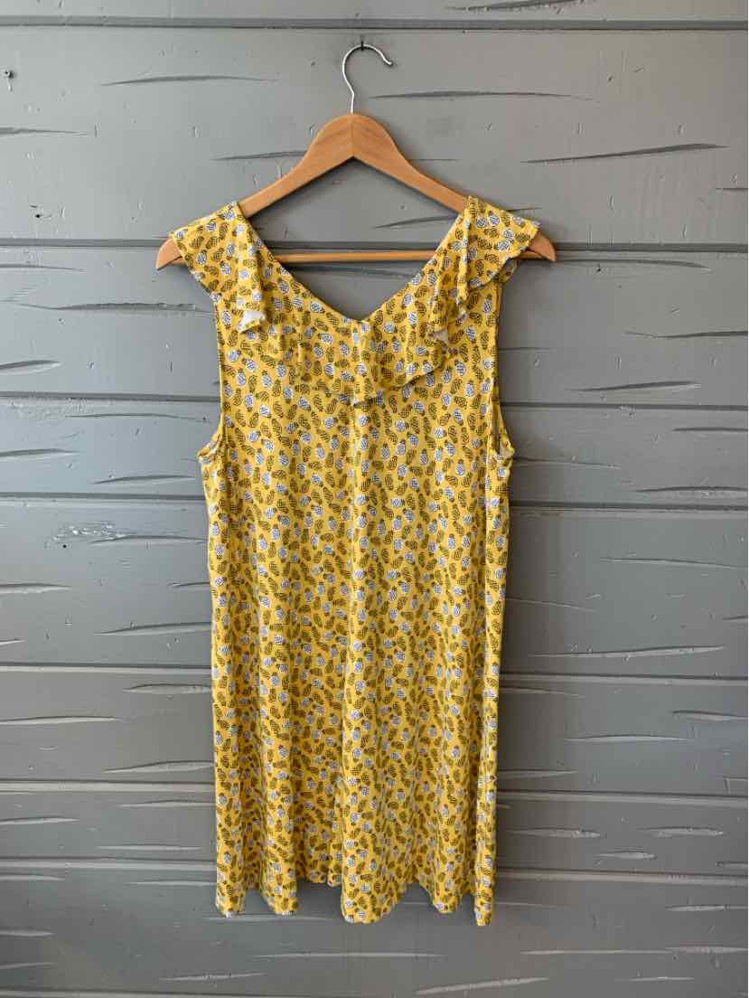 Yellow pineapple print sleeveless dress with ruffled neckline on wooden hanger.