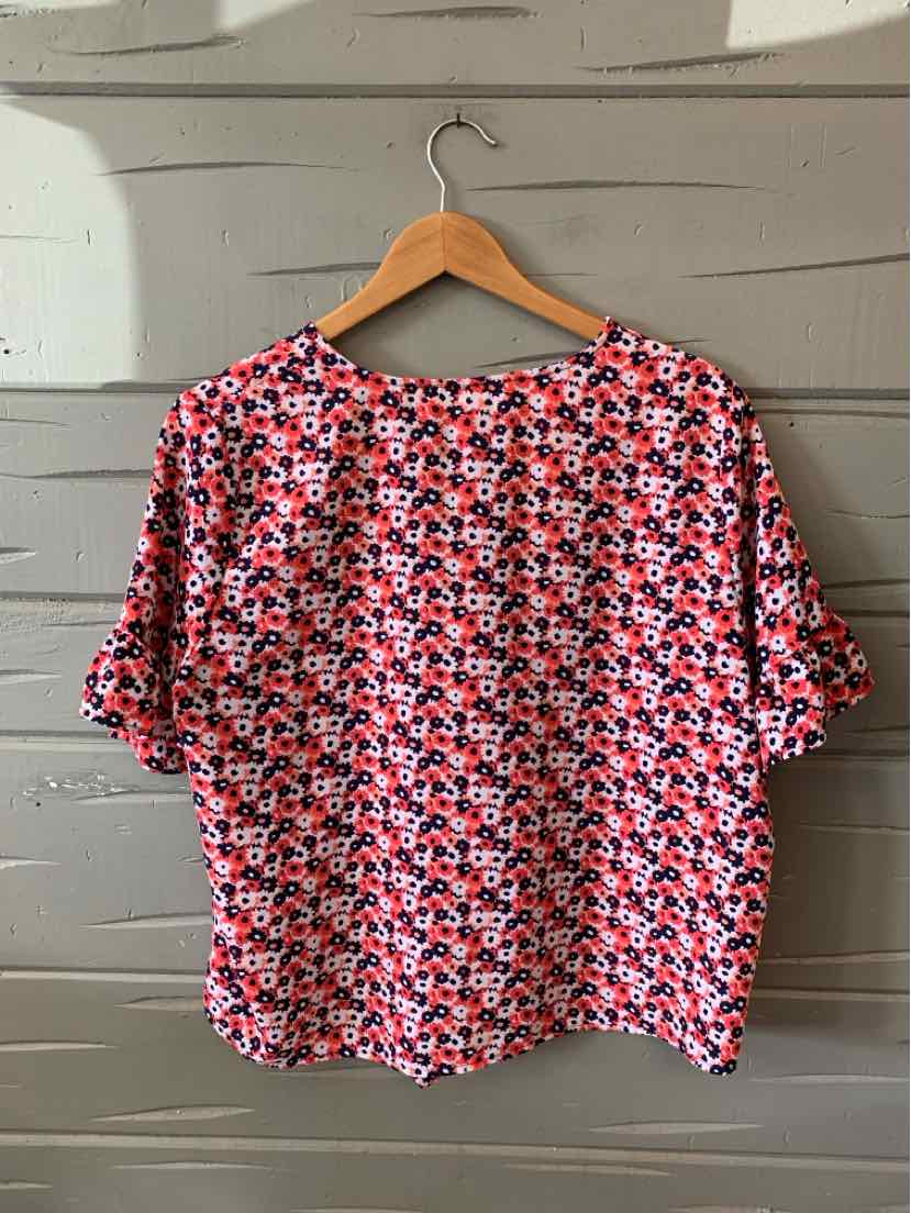 Pink floral Michael Kors blouse with short sleeves and relaxed fit on wooden hanger.