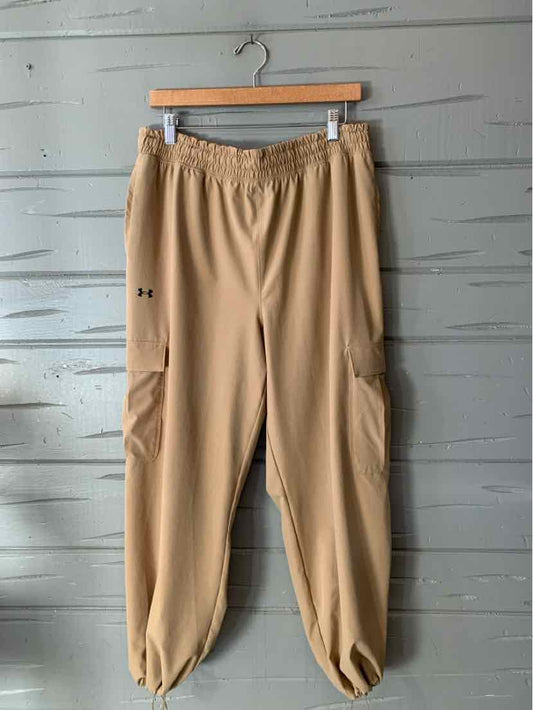 Tan Under Armour jogger pants with an elastic waistband, side pockets, and gathered cuffs.