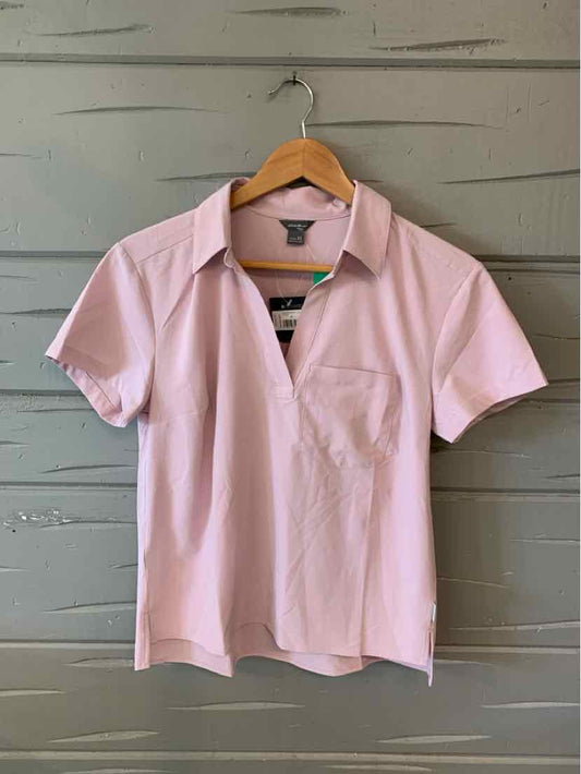 Light pink short-sleeve polo shirt with collar and front chest pocket on wooden hanger.