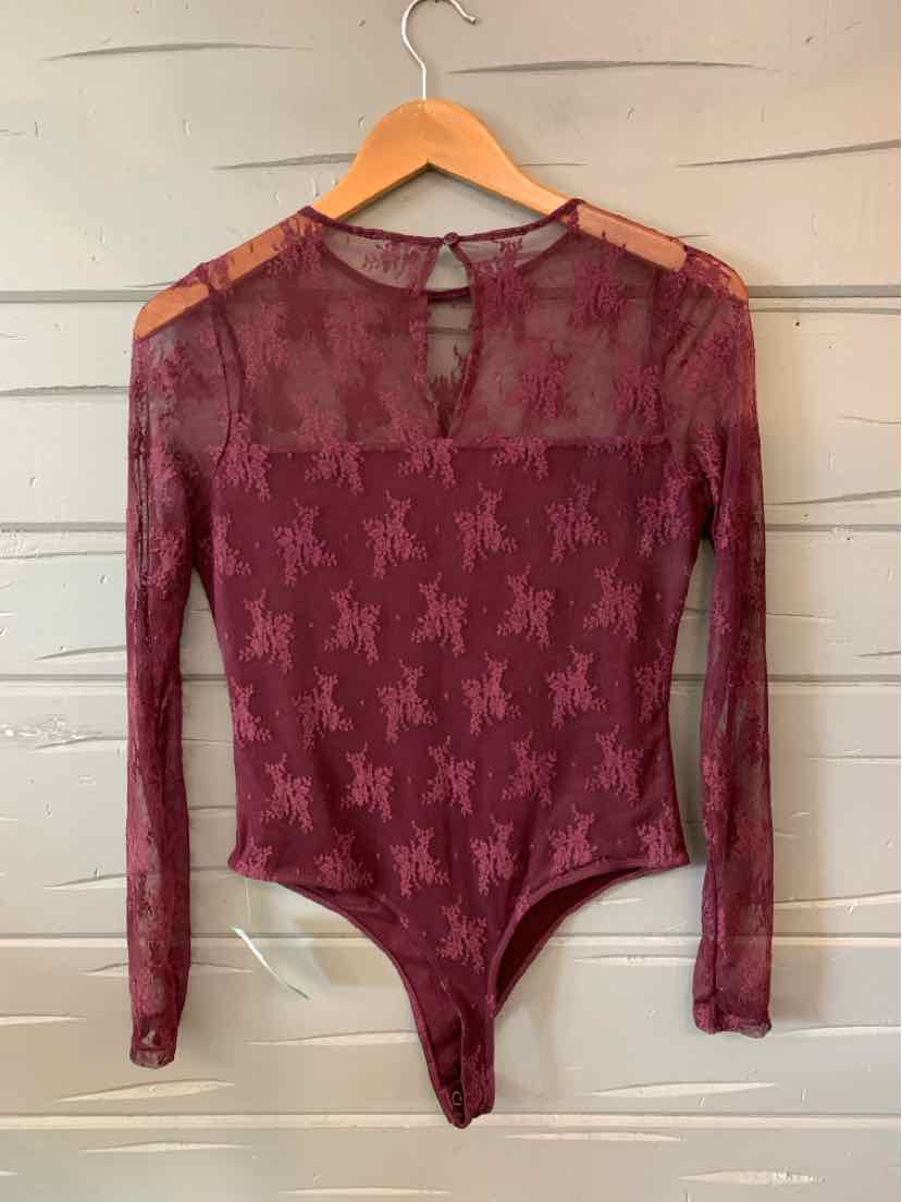 Long-sleeve sheer burgundy bodysuit with star pattern and keyhole neckline on wooden hanger.
