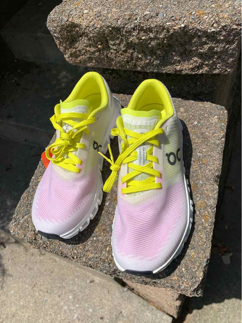 Pink and neon yellow running sneakers with white soles and black "On" logo on the side.