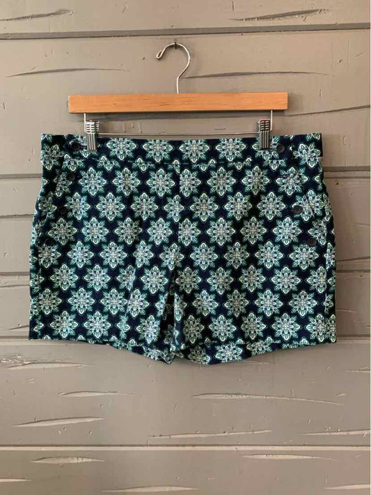 Black and teal patterned shorts with a floral geometric design, size 14, hanging on wooden hanger.