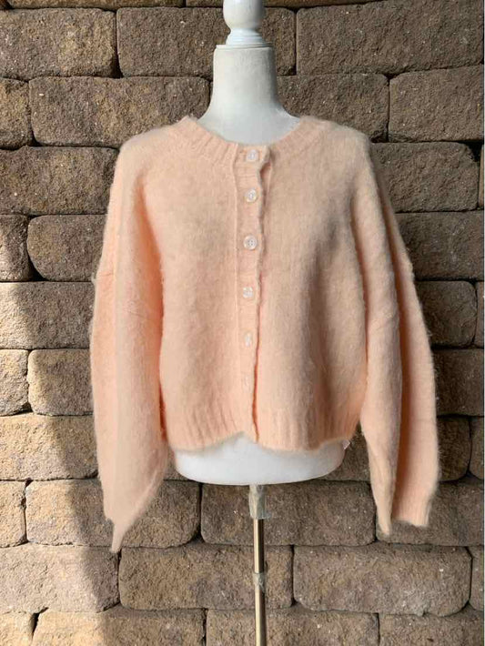 Peach fuzzy knit cardigan with a round neckline, button front, and cropped, boxy fit.
