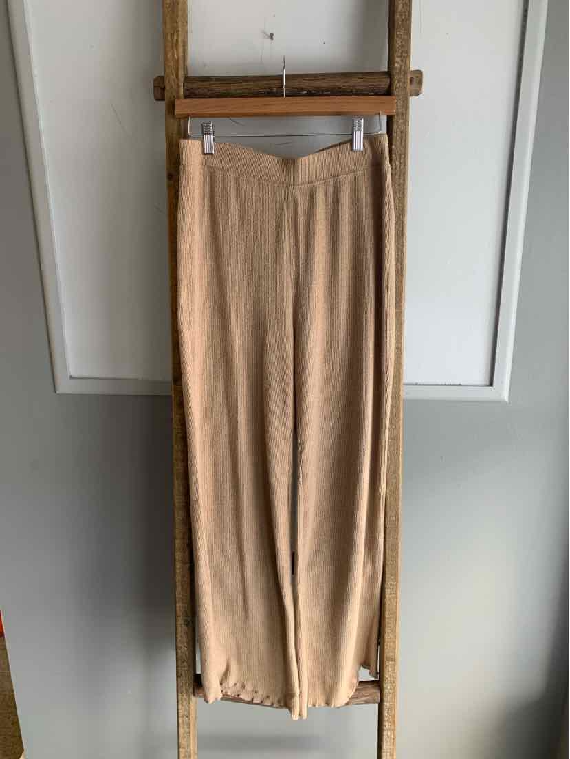 Tan wide-leg pants with an elastic waistband and soft, lightweight fabric hanging on a wooden ladder.