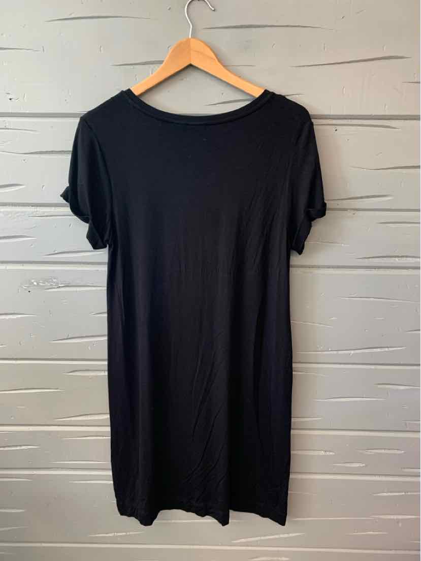 Black short-sleeve casual dress with round neckline on wooden hanger against gray wall.