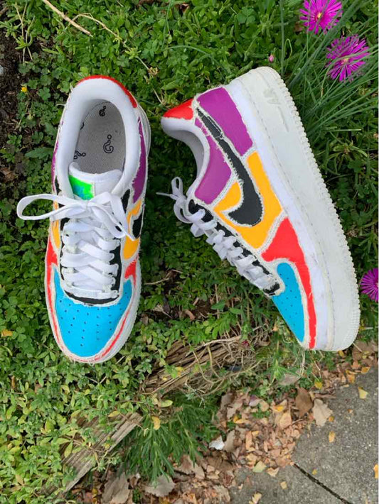 Pair of multicolor Nike sneakers with turquoise mesh toes, white laces, bright orange and yellow panels, and white soles.