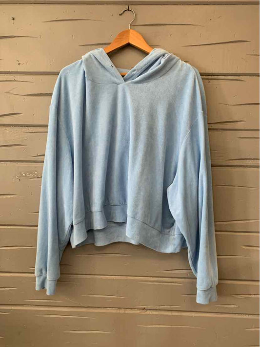 Light blue oversized hoodie with kangaroo pocket and drawstring hood hanging on wooden hanger.