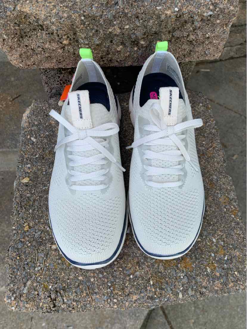Beige knit fabric sneakers with white laces, black collar lining, and green pull tabs at the heel, size 8.