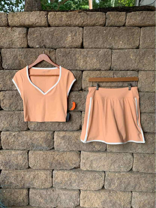 Peach-colored short-sleeve crop top and matching athletic shorts with white trim, soft fabric, casual activewear set.
