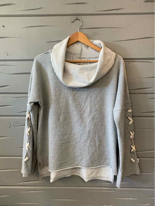 Gray long-sleeve sweatshirt with a wide cowl neck and lace-up sleeve details, hanging on a wooden hanger.