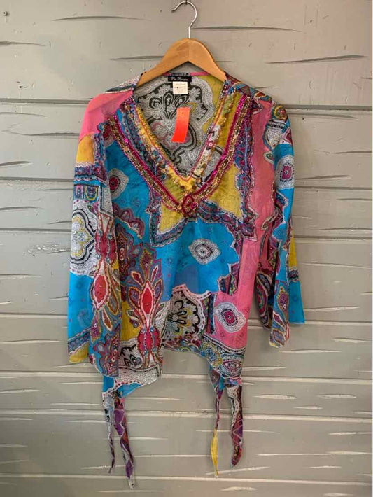 Colorful bohemian multi-patterned blouse with ruffled collar and asymmetrical hem on wooden hanger.