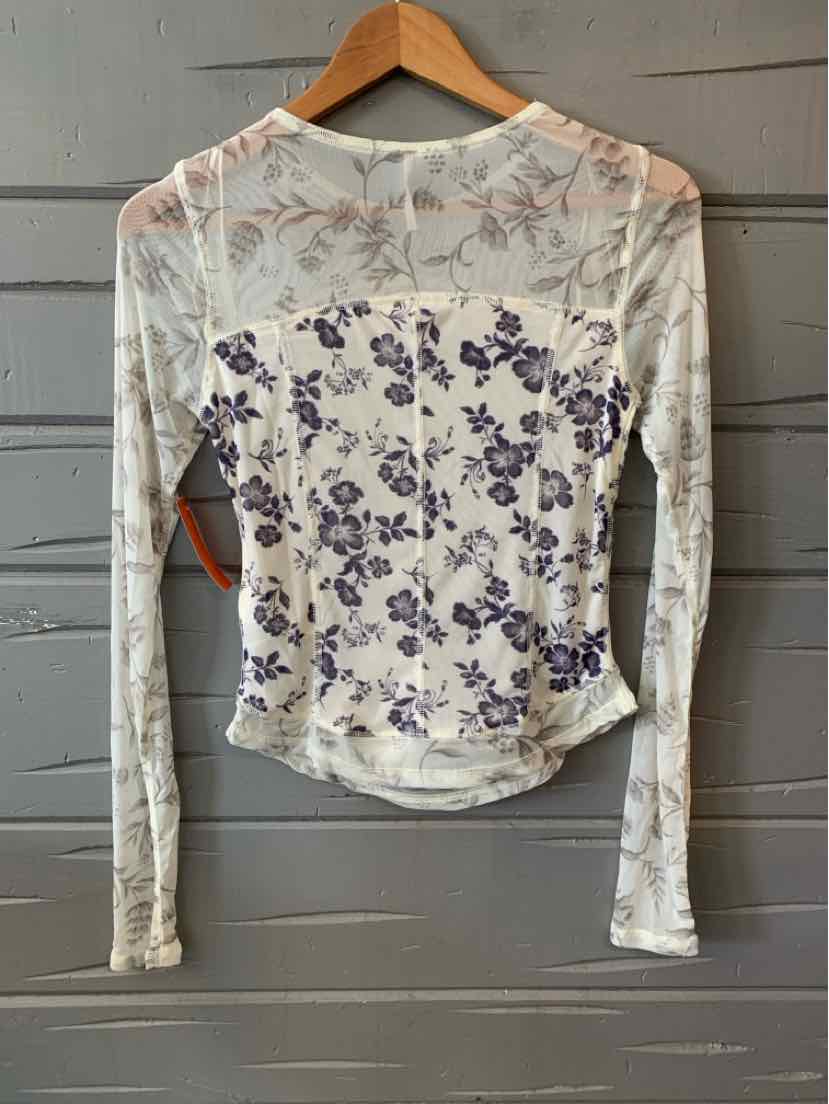 White long-sleeve floral mesh top with purple flower prints and ruched sides on a wooden hanger.