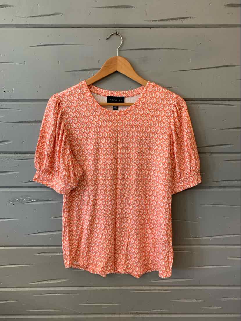 Orange floral-patterned blouse with puffed elbow-length sleeves on a wooden hanger.