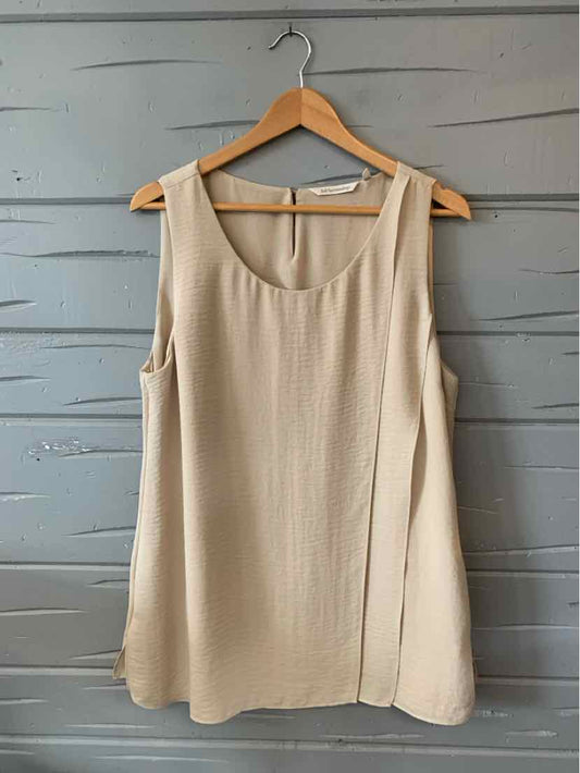 Tan sleeveless blouse with scoop neckline and relaxed fit hanging on wooden hanger.