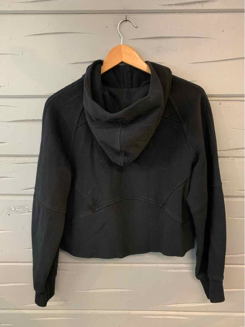 Black cropped hoodie with long sleeves and a fitted silhouette hanging on a wooden hanger.