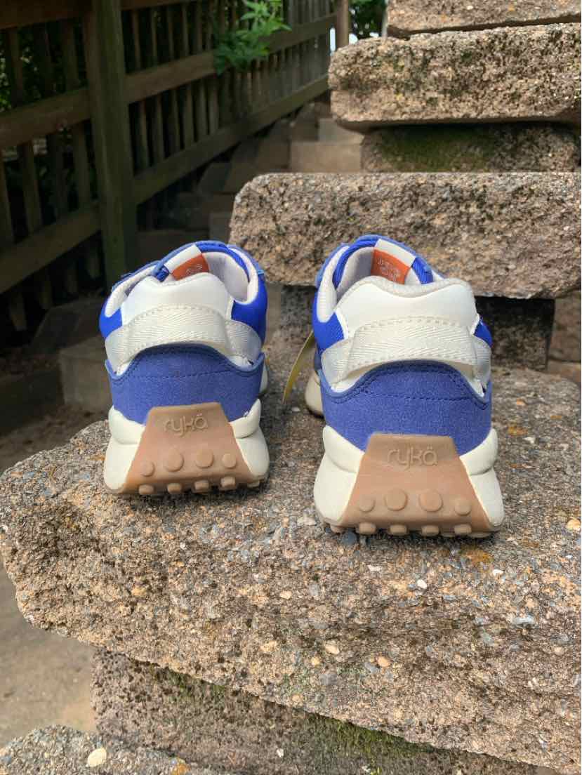 Blue and white athletic sneakers with beige rubber soles, velcro strap, and mesh fabric back view.