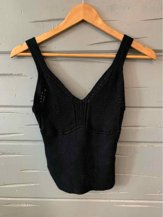 Black knitted tank top with wide straps and V-neckline on wooden hanger.
