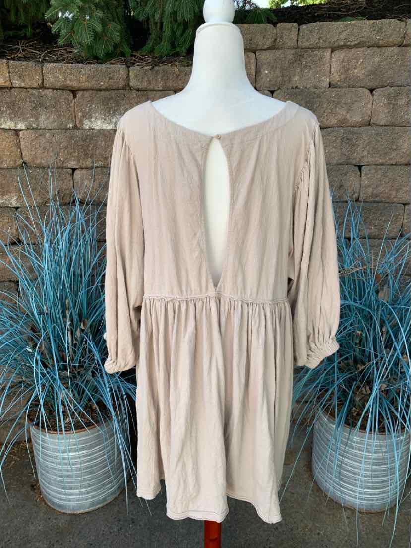 Beige long-sleeve dress with gathered waist and keyhole back cutout in lightweight fabric.