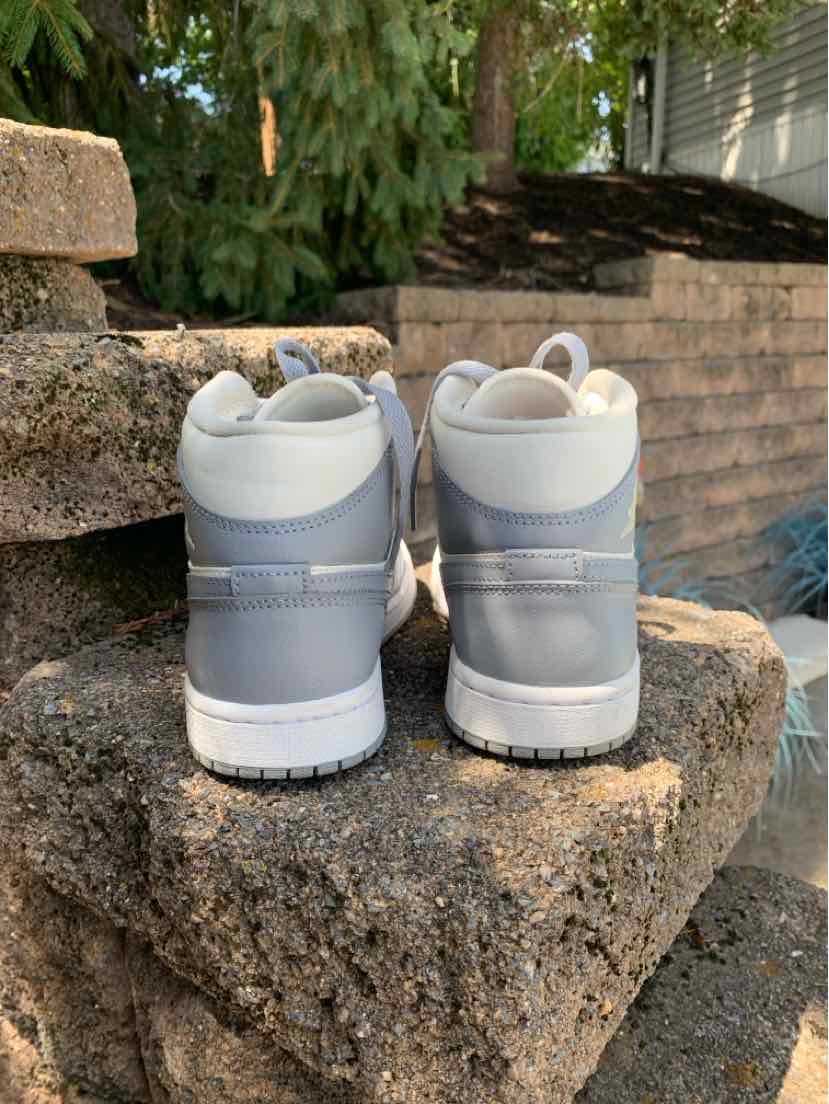 White and light gray Nike sneakers with padded collar and white sole, women's size 6.5, rear view.