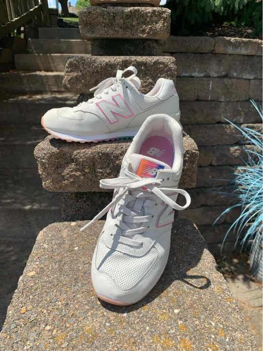 Light gray New Balance sneakers with pink "N" logo, white laces, and cushioned soles, size 9.