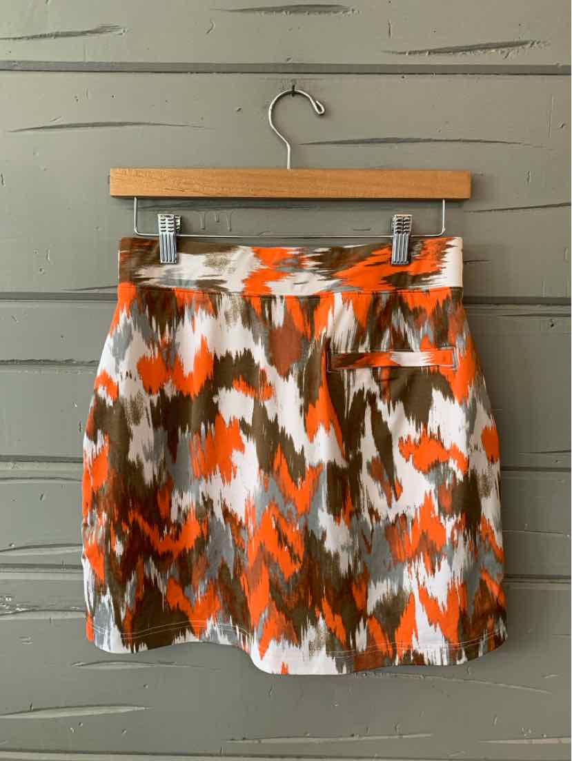 Orange, white, and brown abstract patterned skirt with side pocket hanging on wooden hanger.