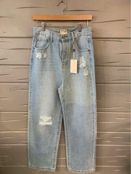 Light blue denim jeans with distressed details, high waist, and straight leg cut hanging on wooden hanger.