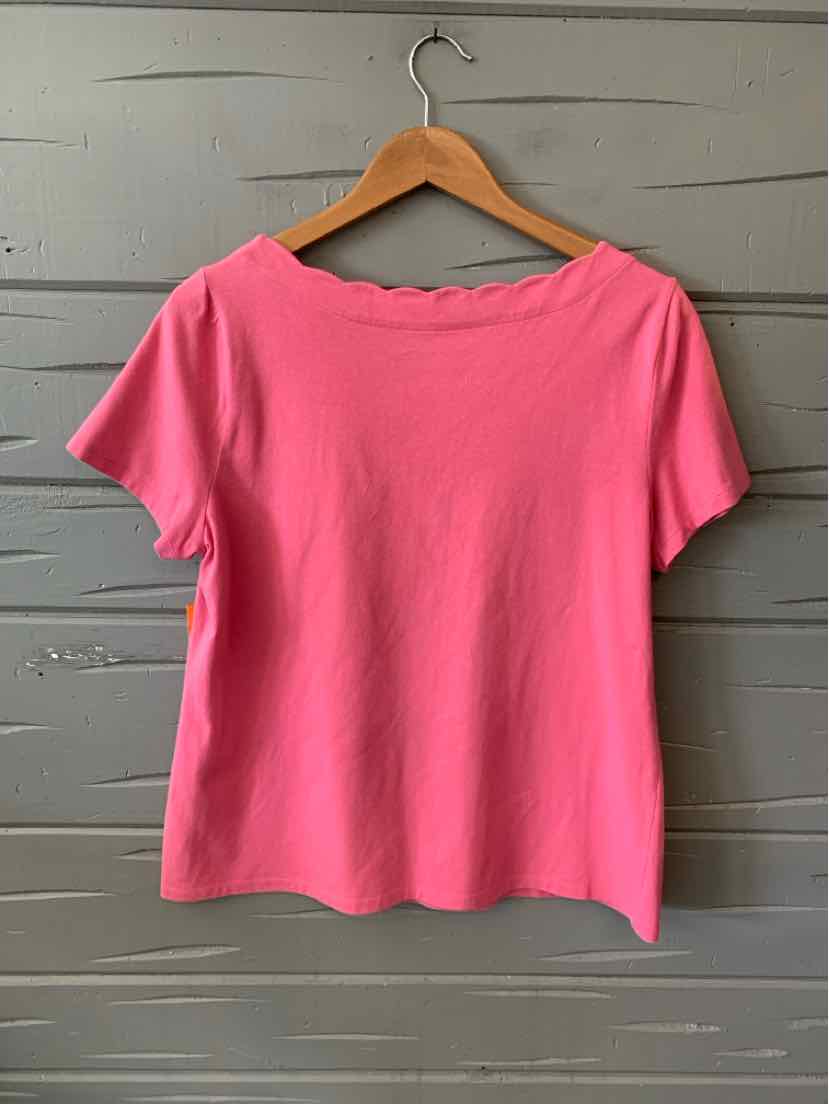 Solid bright pink short-sleeve top with scalloped neckline on wooden hanger.