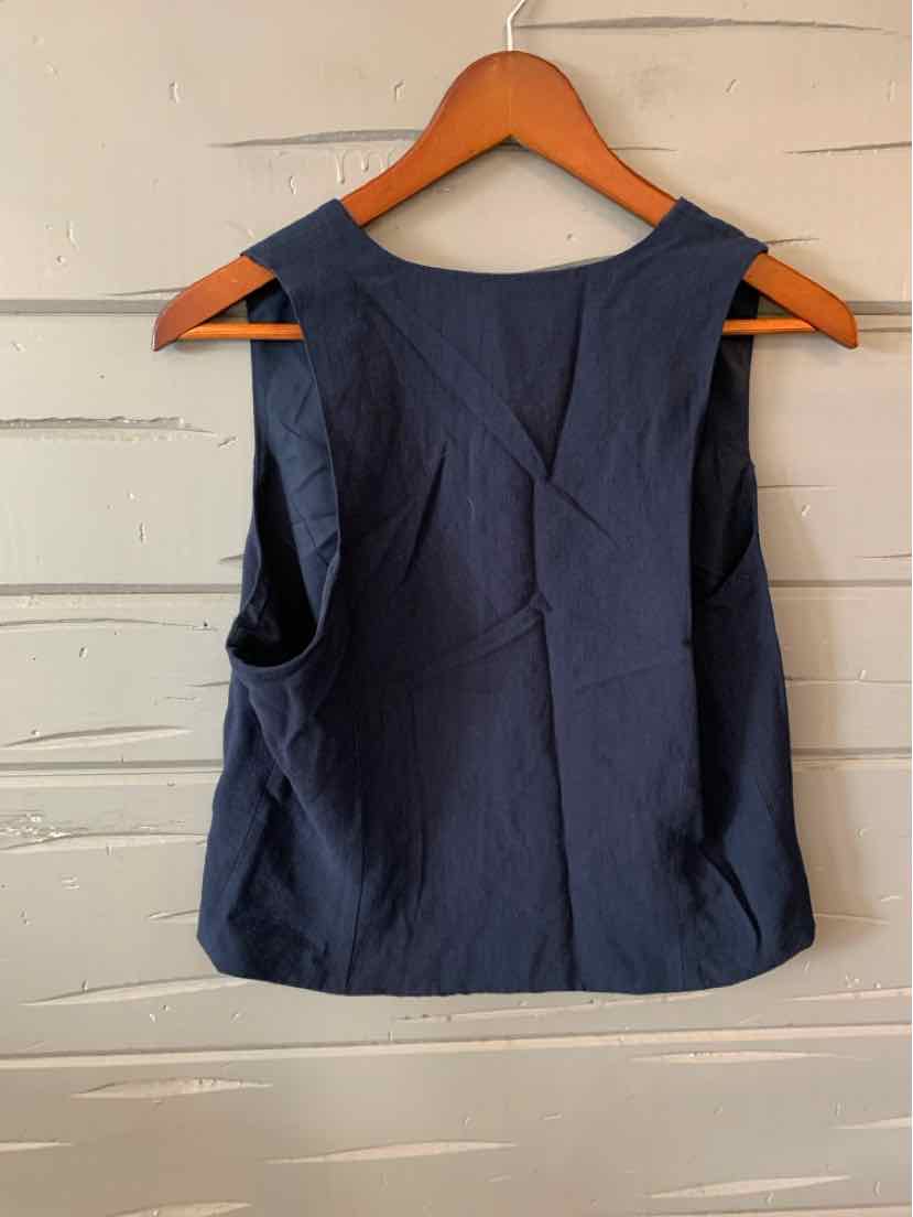 Sleeveless navy blue top with a round neckline and a clean, solid fabric design hanging on a wooden hanger.