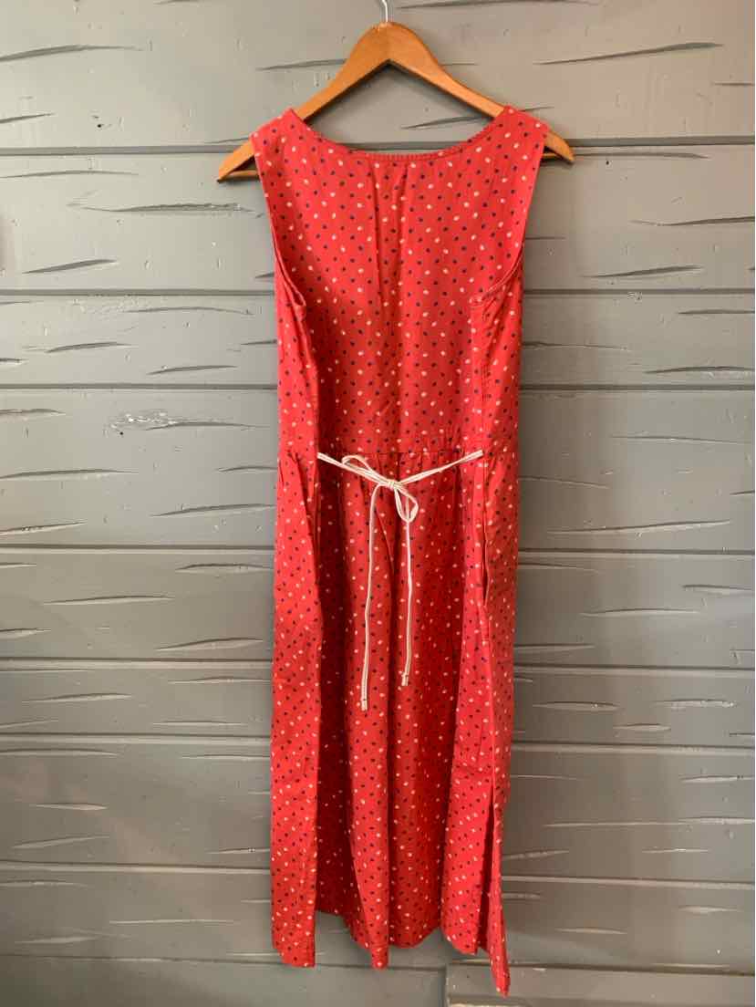 Red sleeveless midi dress with small white floral print and white waist tie belt on wooden hanger.
