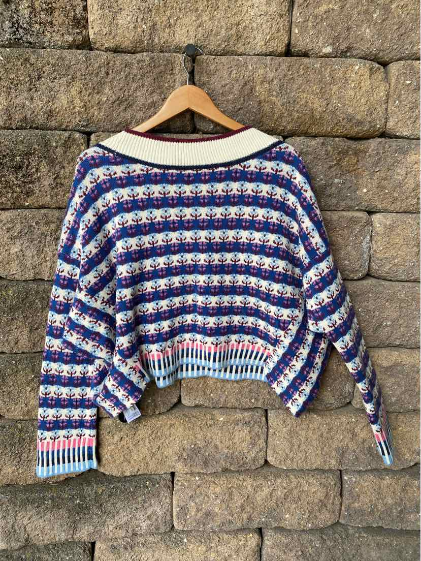 Crocheted multi-color sweater with blue, white, red, and pink stripes, oversized fit, and ribbed cuffs and hem.