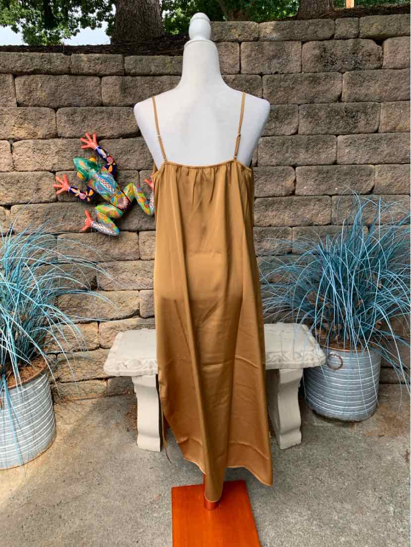 Sleeveless tan midi dress with thin straps and a loose, flowing fit on a mannequin outdoors.