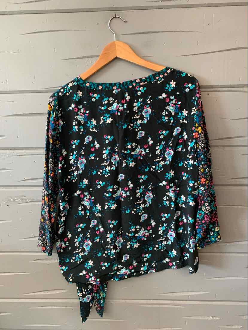 Black floral blouse with teal, pink, and white flowers, long sleeves, and a tied hem.