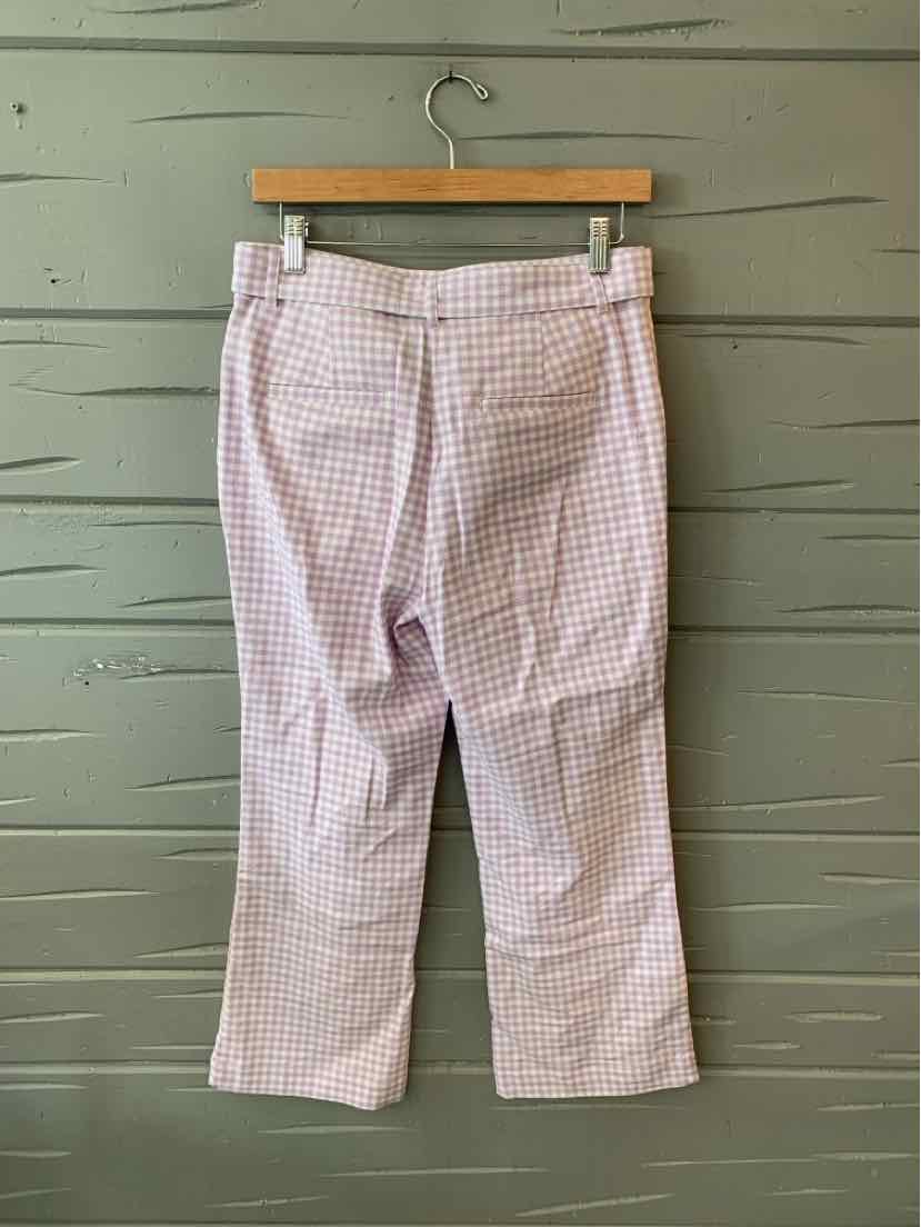 Light pink and white gingham cropped pants with wide waistband and straight legs hanging on wooden hanger.